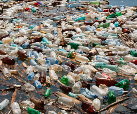 a photo of many dirty, used plastic bottles littering the beach. 