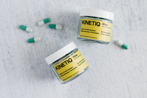 Bottles of Kinetiq Glow and capsules on marble table