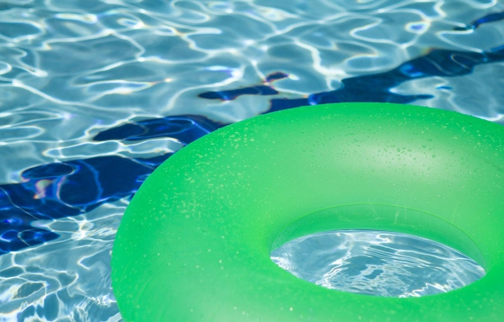 Green raft floating in clean in-ground pool
