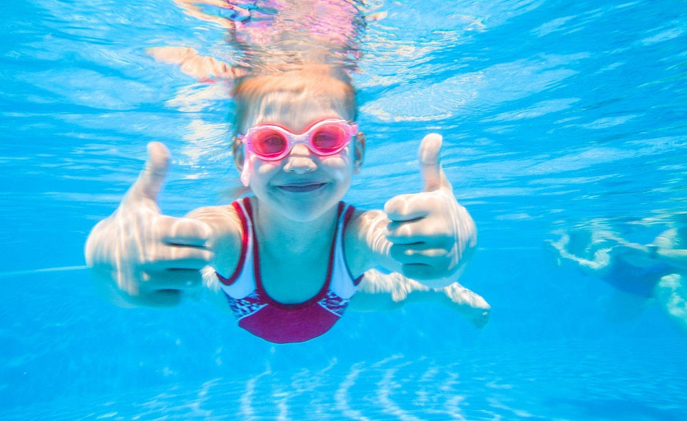 Little girls swimming underwater giving thumbs up