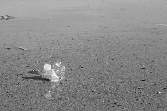 discarded single use plastic water bottle littering a beach