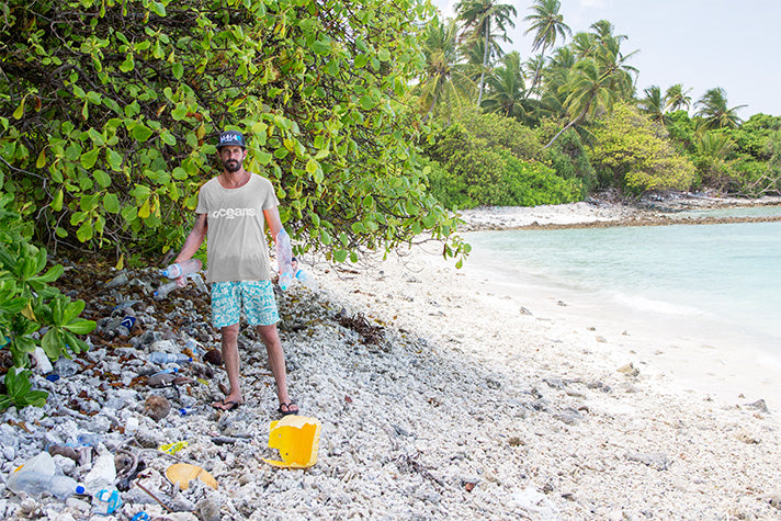 surf guide felippe dal pierro clearing plastic bottles from a beach in the maldives