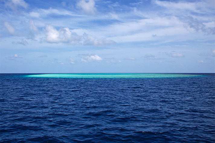 ocean with a patch of shallow coral reef in the maldives