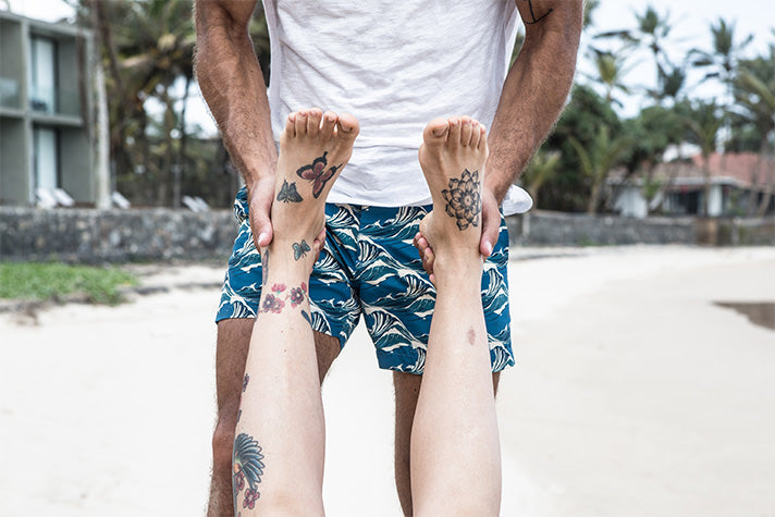 Holistic massage therapist Franco Rebagliati at work on the beach in Sri Lanka, holding a patient's tattooed feet