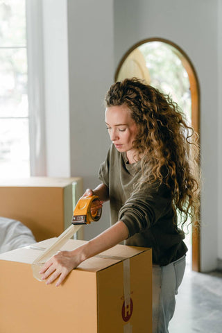 woman packaging and securing a large brown box