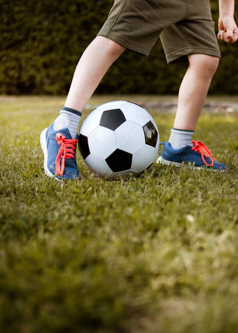 Boys feet in trainers kicking a football