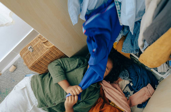 woman lying under a heap of used maternity clothes