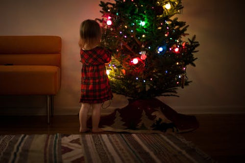 little girl in a christmas dress decorates the tree