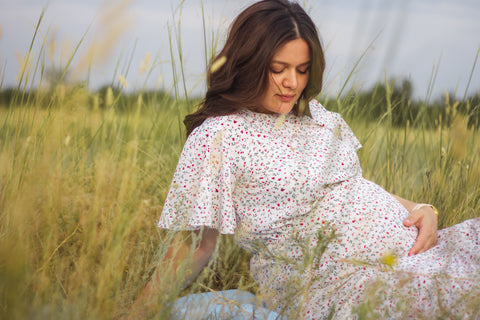 Pregnant woman sitting in a field of grass