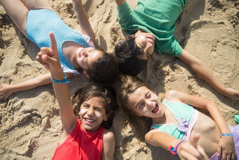 Summer Holiday kids friends lying in a circle on the beach