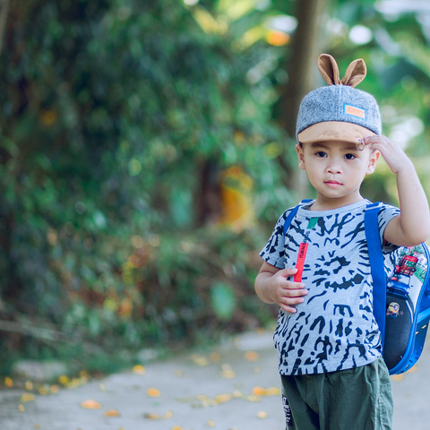 a preschool boy wearing a cap and rucksack