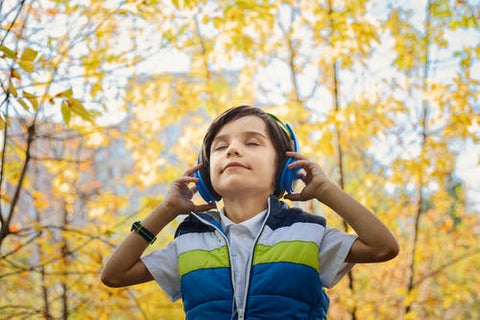 an older boy wearing a gilet in the autumn sunshine wearing headphones