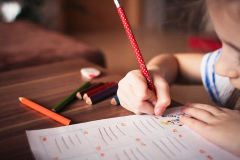 a young girl wearing school uniform writing on some paper