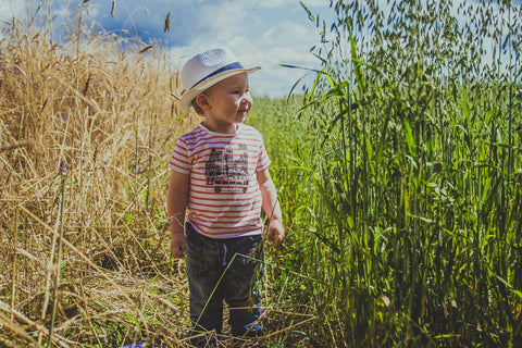 A Toddler Boy UK in field of corn wearing a striped t-shirt and hat