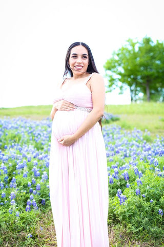 Pregnant woman in a dress in a field of bluebells