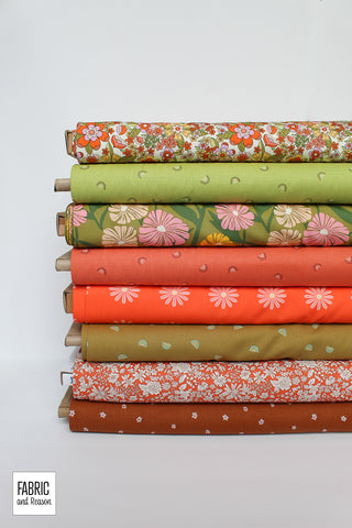 Stack of eight bolts of fabric laid horizontally. All fabrics include prints: florals, and mini rainbows in shades of green, orangey red, and pink.