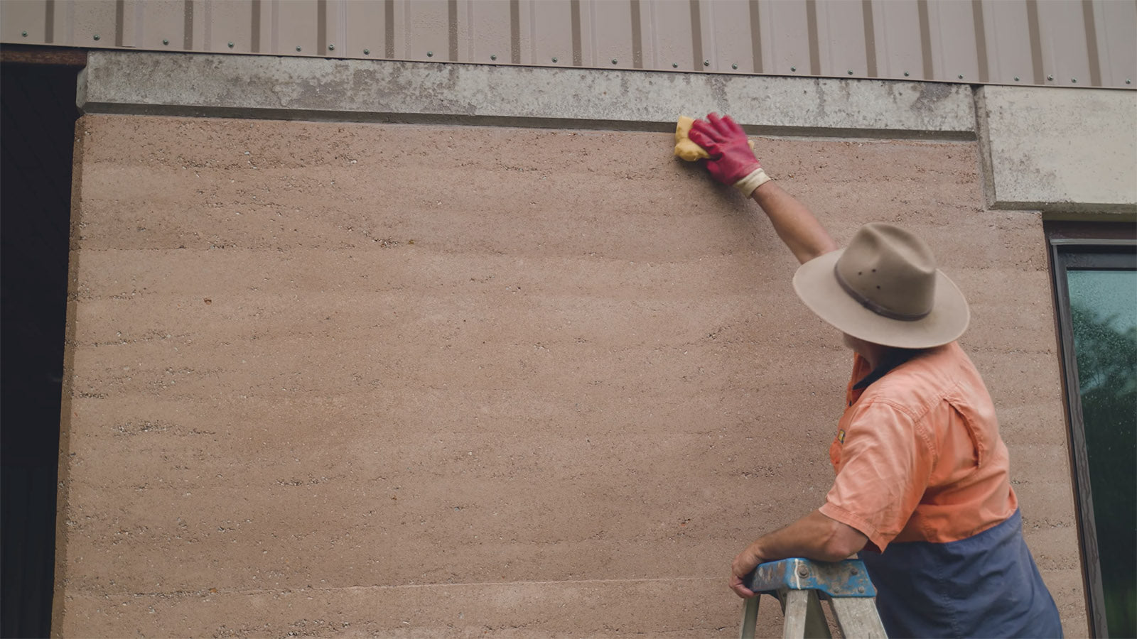 Photo of man cleaning a rammed earth wall