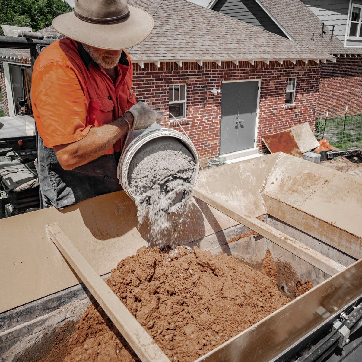 Photo of man mixing soil to prepare for rammed earth walls.