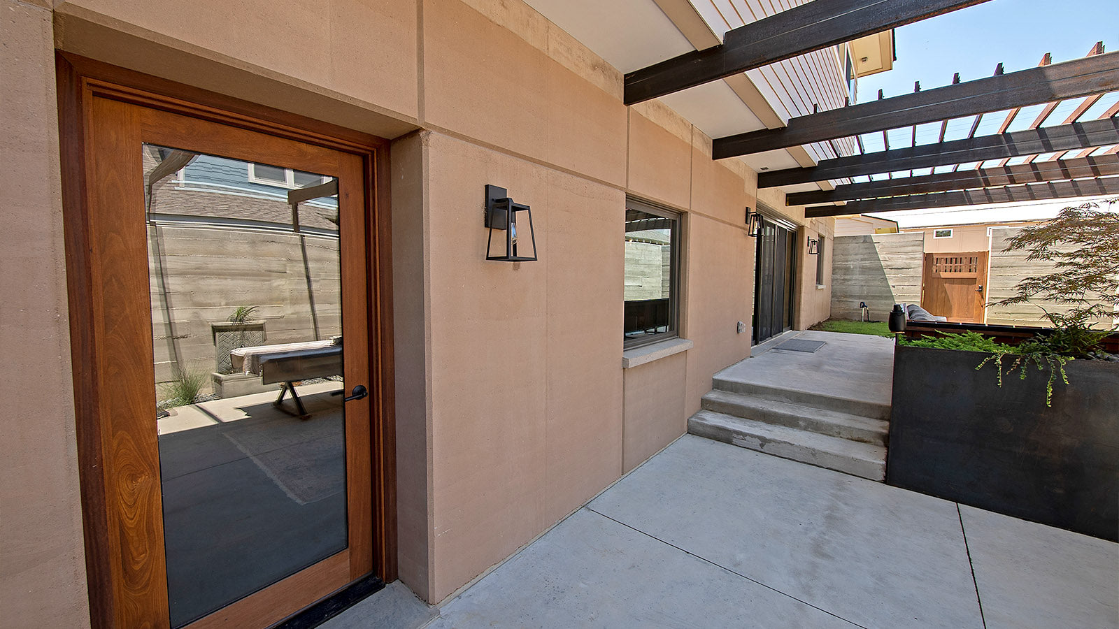 Photo of rammed earth exterior walls leading to a residential patio