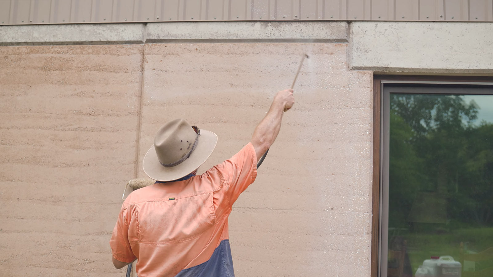 Photo of man spraying water repellent on rammed earth wall