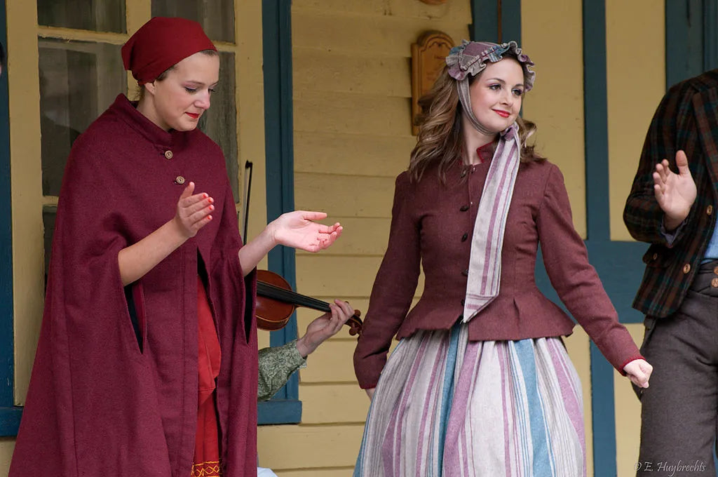 Deux femmes vêtues de robes, lié à la culture du village québécois d’Antan sorti tout droit du 19e siècle.