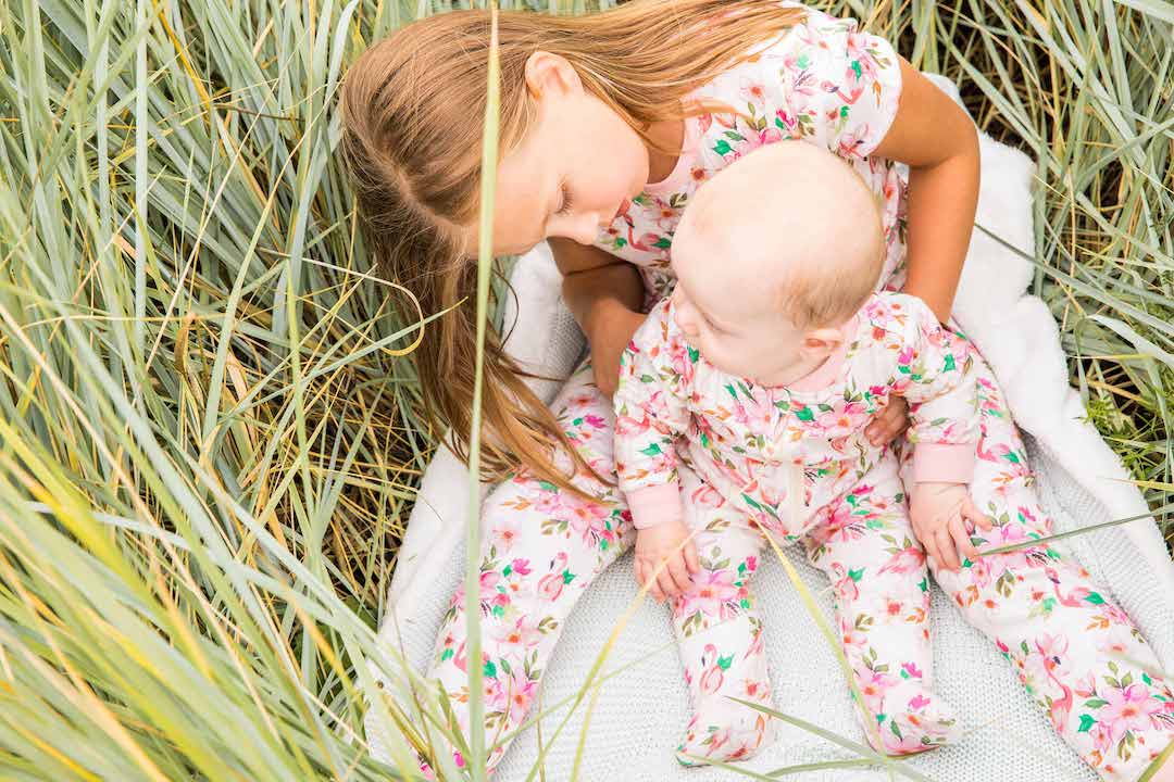 Bébé porte un Pyjama Une Pièce en Coton Bio Imprimé Flamants Beiges.