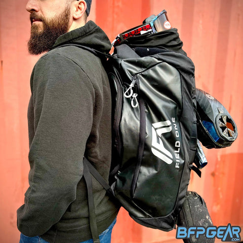 Kyle from Field One with the AW Gear Backpack on. Goggle system is secured to the top MOLLE panel, a full paintball marker setup is secured to the rear buckled straps and the backpack is filled with gear.