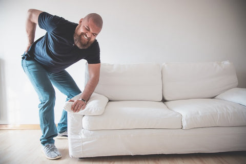 man with sore back from moving heavy household furniture