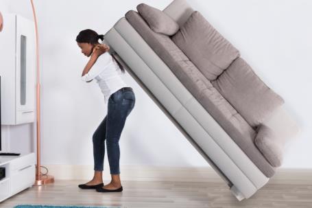 woman struggling to move heavy household furniture