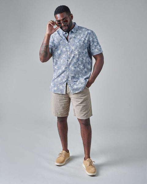 A man dressed in casual shorts, shoes, and a buttoned short-sleeved shirt