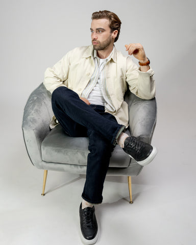 Man in a button-down, jacket, jeans, and leather sneakers