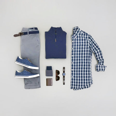 A flatlay of a button-down, sweater, chinos, and sneakers