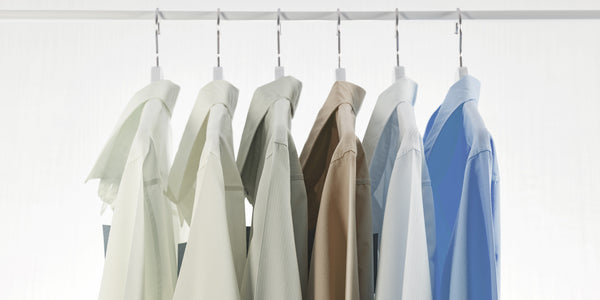Mens dress shirts in an array of pastel colors hanging on a clothing rail.