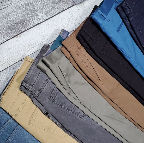 An assortment of jeans, chinos, and slacks on a gray background.