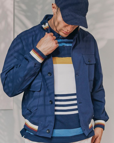 A man wearing a horizontal stripe shirt, blue jacket and cap