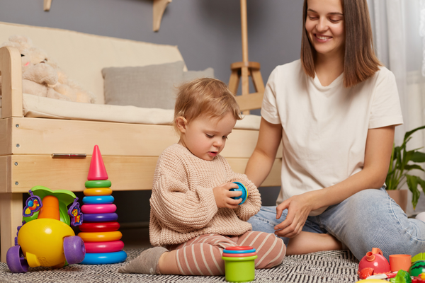 A mother and child sitting on the floor and playing with child's toys