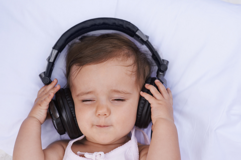 Baby of under a year with headphones on and closed eyes.