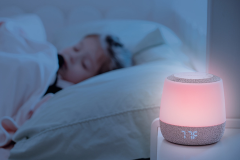 Babysense Dreamer shining pink while a child sleeps in the background