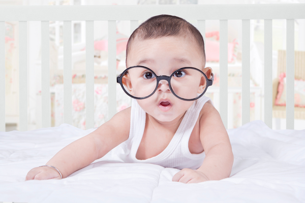 Baby lying on stomach with black round glasses