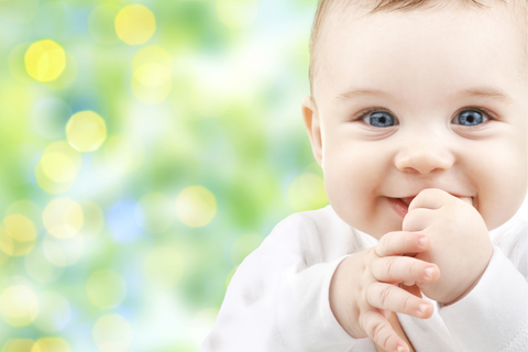 Baby with blue eye holding hands to mouth