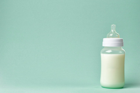 Baby bottle with milk on a green backgound