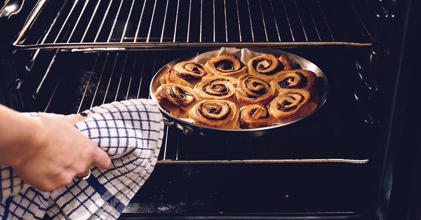 Person taking cinnamon rolls out of the oven.