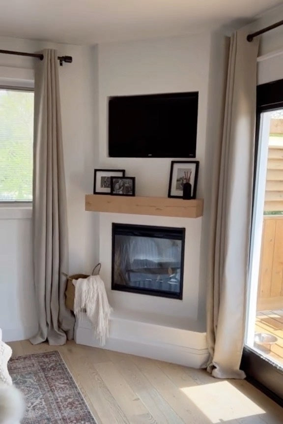 Bump-out corner fireplace with wood mantel in a bright bedroom.