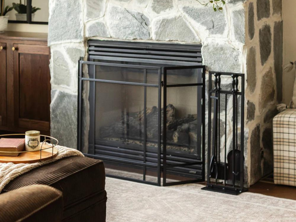 Close up of a fireplace with screen and tool accessories to the side.