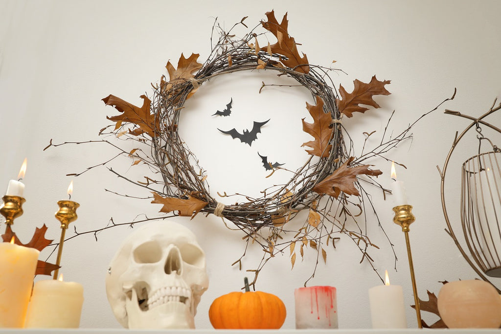 A fall leaf wreath, pumpkins and candles on a fireplace mantel.