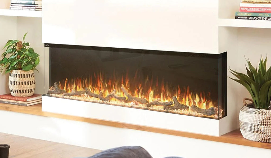 Multi sided electric linear fireplace in a white wall with plants on either side.