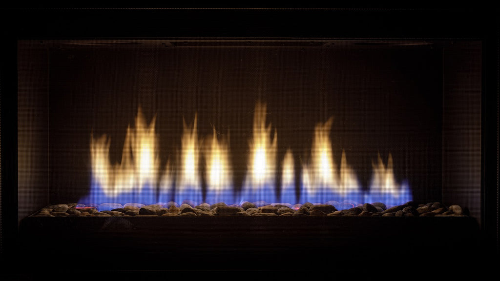 Close up of gas fireplace burning with blue and orange flame.