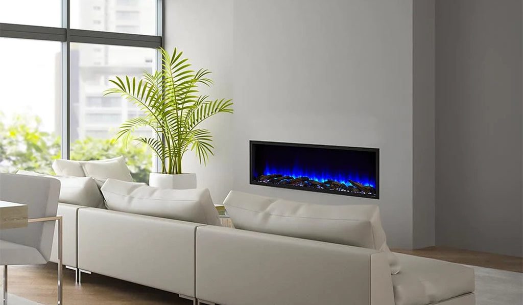 Electric fireplace in the wall with blue flames with white couch in the foreground.