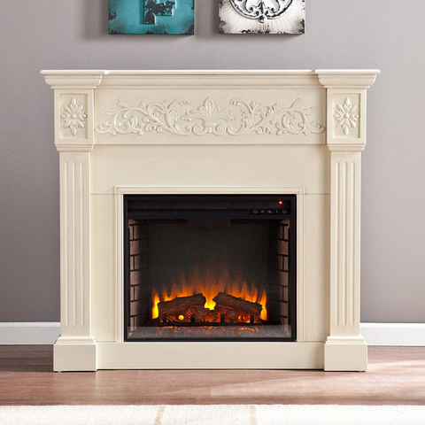 Traditional warm white mantel and surround with ornate wood detailing and an electric fireplace against a gray wall.