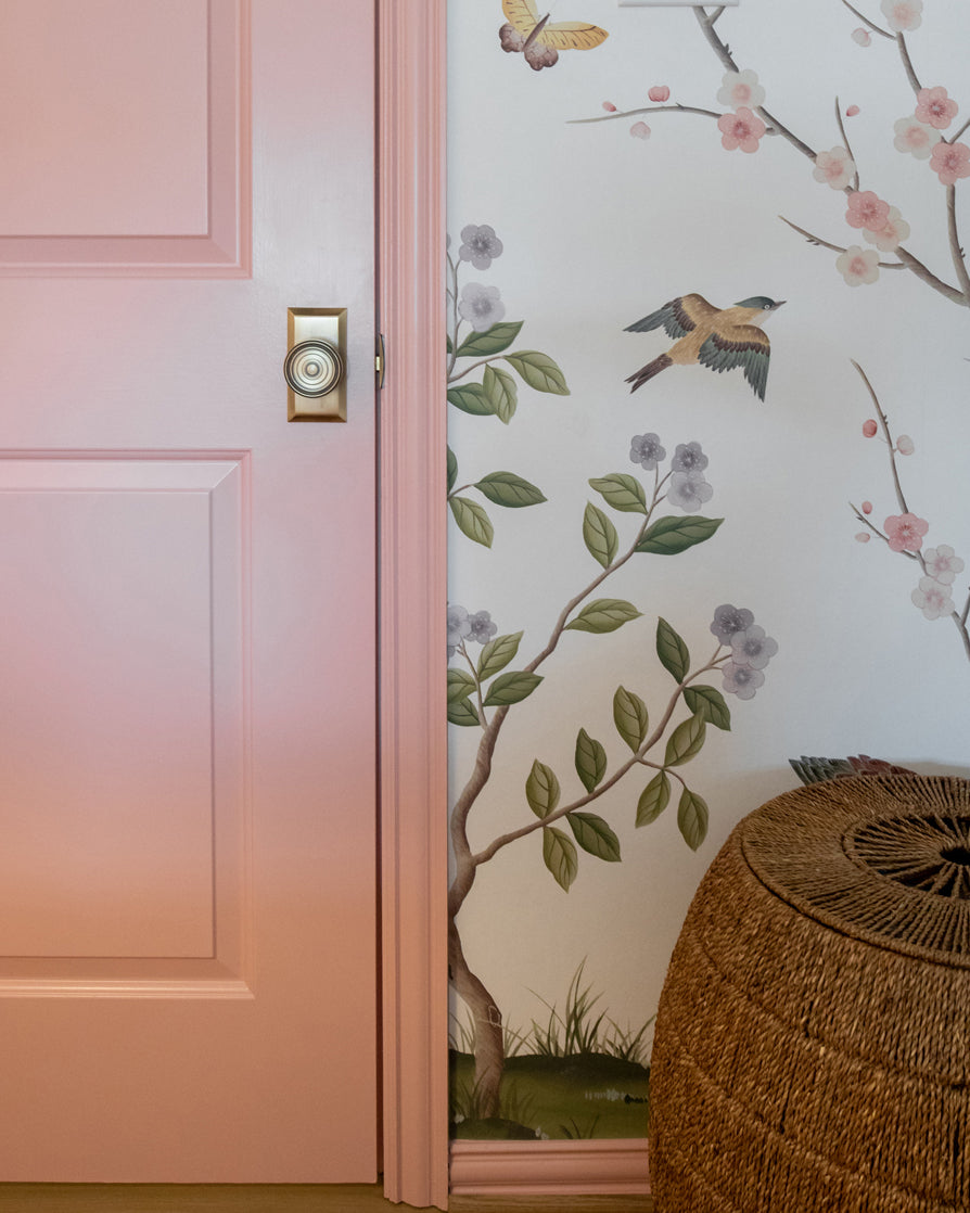 Pink interior door with a Fifth Avenue Short Plate with Soleil Knob in Vintage Brass on it.